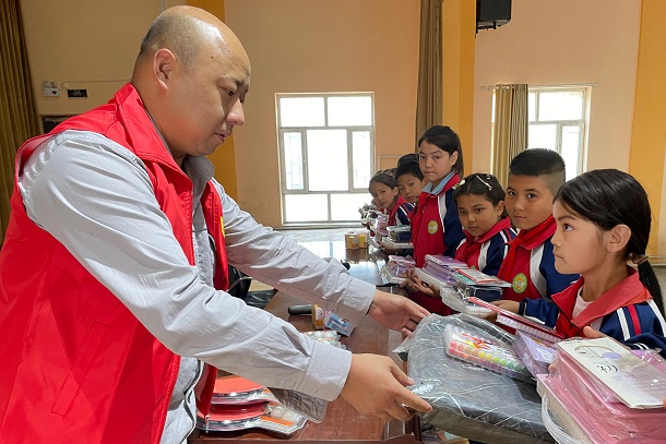 圖為張成國給學生贈送文具