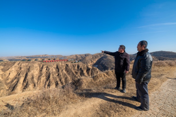 圖為高西溝村黨支部副書記高利東正在和村民一起瞭望遠處的光伏板
